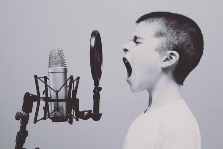Young boy screaming into a microphone simbolizing loud noise