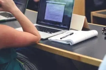 Girl studying while wearing noise-cancelling headphones to better focus on her class paper