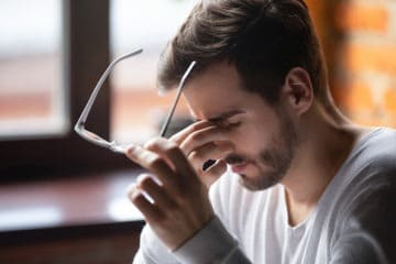 Man having a headache and wondering if his headphones can cause cancer